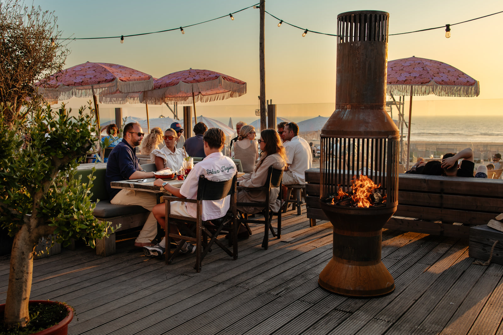 Gasten aan tafel op een strandterras met de VENTOR® Original brandend ernaast
